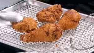 Easy Fried Chicken - Crispy fried chicken pieces resting on a wire rack over a baking sheet _ Chef Jean-Pierre